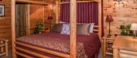 Un dormitorio tipo cabaña de madera con cama con dosel, cortinas rojas y dos lámparas de noche.