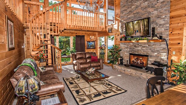 Un salón amplio con chimenea, paredes de madera y un balcón.