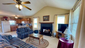 A living room with a fireplace, a television, and a ceiling fan.