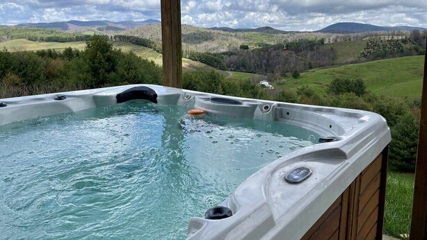 A hot tub with a view of rolling hills and mountains.