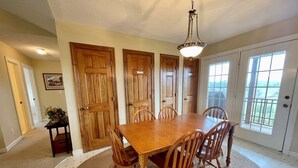 A dining area with a wooden table and chairs, a rug, and a chandelier.