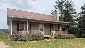A single-story house with a porch, a chimney, and a satellite dish.