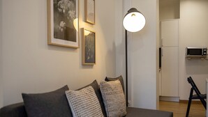 En moderne stue med sofa, gulvlampe og billeder i rammer på væggen.