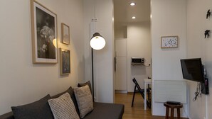 En moderne stue med en grå sofa, en gulvlampe og billeder på væggen.
