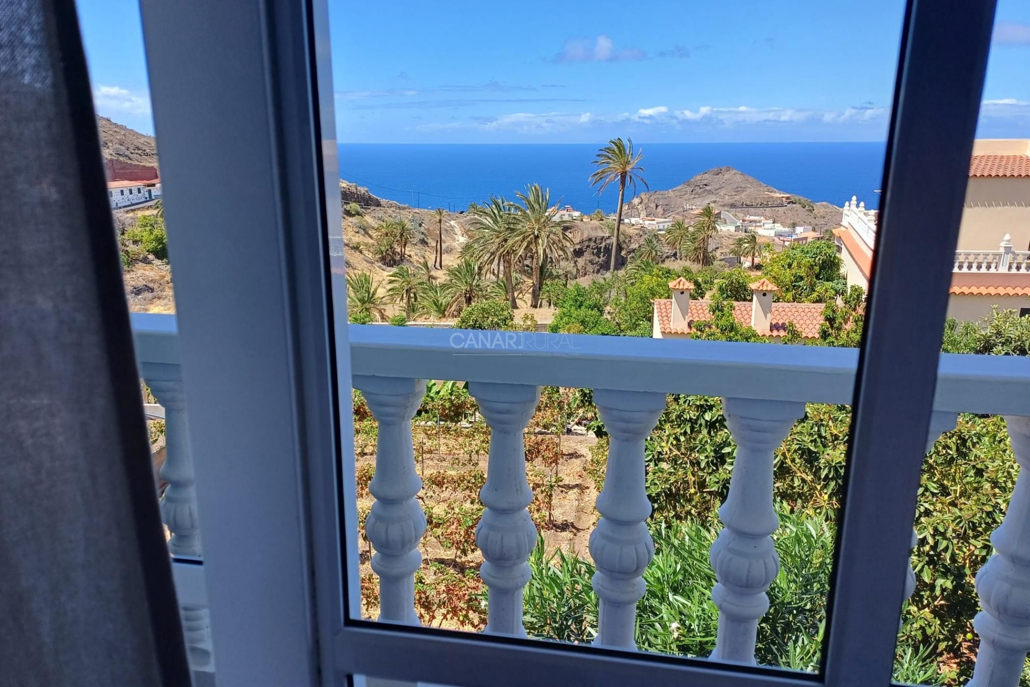 Un balcon offrant une vue sur un paysage côtier, comprenant une colline et la mer.