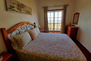 Un dormitorio con una cama grande, un aparador, un espejo y una ventana con vistas.