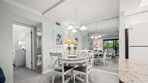 Une cuisine moderne avec des meubles blancs, un coin repas doté d’une table ronde et de chaises, et une vue sur l’extérieur.