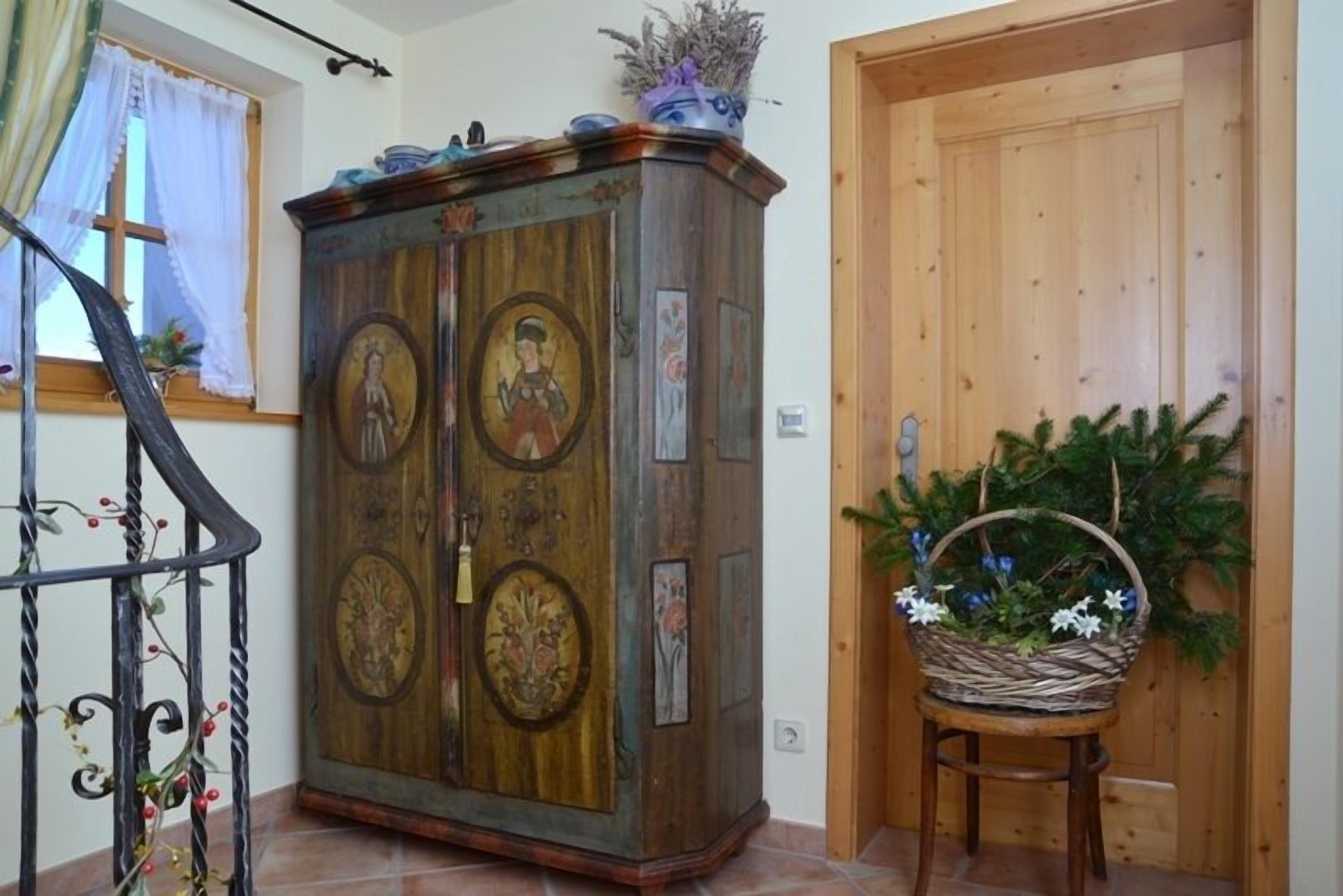Un meuble en bois orné de peintures religieuses, un panier en osier rempli de fleurs et une porte en bois.