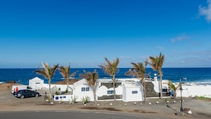 A coastal property with white buildings, palm trees, and a view of the ocean.