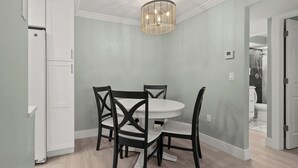 A dining area with a round table and four chairs, a white ceiling, and a modern light fixture. - Newly Renovated Partial Beach View 1 bed, 1 bath at Sanibel Moorings #131 (Sanibel)
