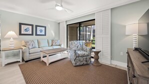A living room with a sofa, armchair, coffee table, and a ceiling fan. - Newly Renovated Partial Beach View 1 bed, 1 bath at Sanibel Moorings #131 (Sanibel)