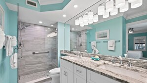A modern bathroom with a glass shower enclosure, a vanity with a marble countertop, and a large mirror.