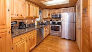 A wooden-paneled kitchen with granite countertops, stainless steel appliances, and wooden cabinets.