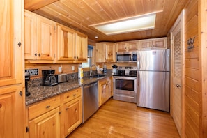 A wooden-paneled kitchen with granite countertops, stainless steel appliances, and wooden cabinets.