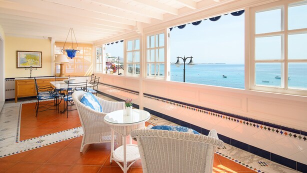 A spacious room with a large window overlooking the sea, a dining area with wicker furniture, and a tiled floor. - Casa Elena, 3 Bedroom Playa Blanca Sea View (Playa Blanca)