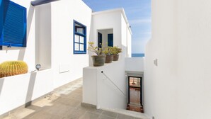 A narrow, white-walled corridor with blue shutters, a small door, and potted plants. - Casa Elena, 3 Bedroom Playa Blanca Sea View (Playa Blanca)