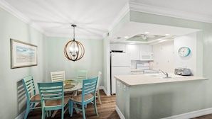 A kitchen with white cabinets, a built-in microwave, and a clock on the wall.