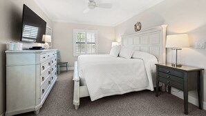 A bedroom with a bed, dresser, nightstand, and ceiling fan.