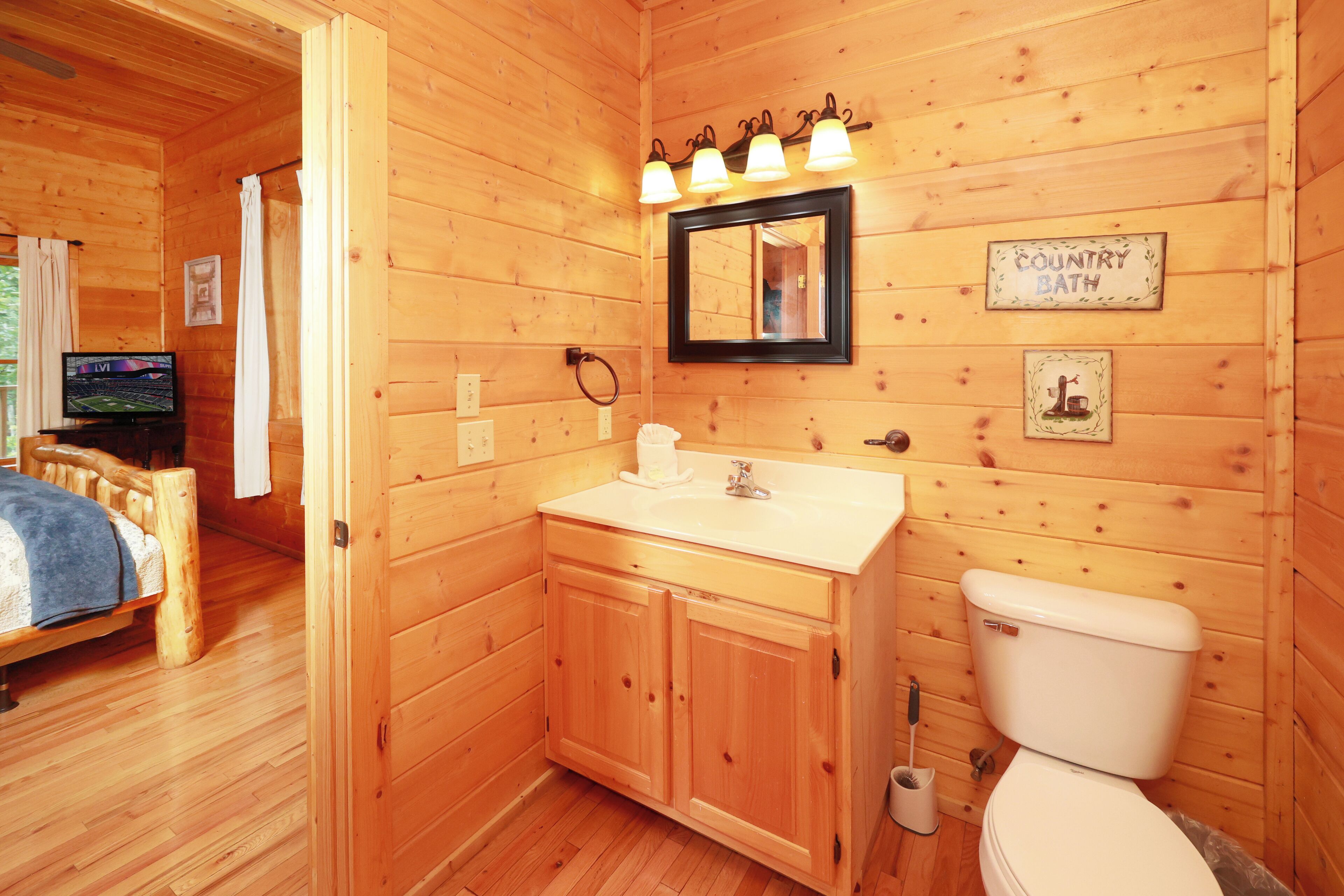 Une salle de bain rustique, aménagée dans une cabane en bois, avec un lavabo, des toilettes et un miroir au-dessus du lavabo.