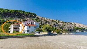 Une propriété située sur la côte, comprenant un bâtiment à deux étages, une allée pavée et une vue sur la mer.