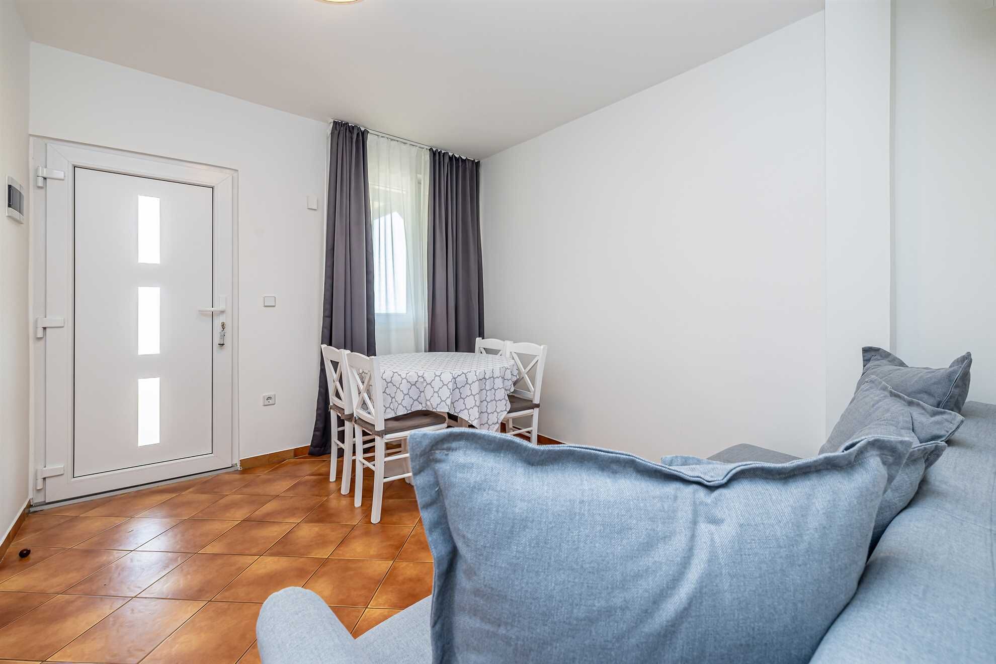 Une pièce comprenant une table à manger et des chaises, un canapé et une porte.