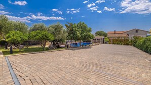 A courtyard with a swimming pool, stone buildings, and trees.