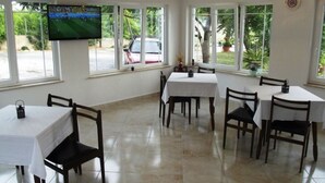 A dining area with multiple tables and chairs, a television mounted on the wall, and large windows with a view of the outside. - Apartment in Supetarska Draga with Seaview, Balcony, Air condition, WIFI (4325-2) (Supetarska Draga)
