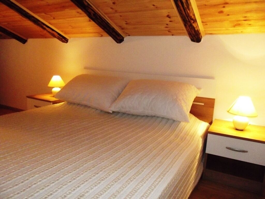 Une chambre à coucher avec un lit, deux tables de chevet avec des lampes et un plafond en bois.