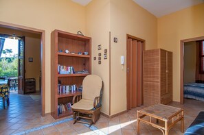 Un salon comprenant une bibliothèque, un fauteuil, une petite table et une armoire.