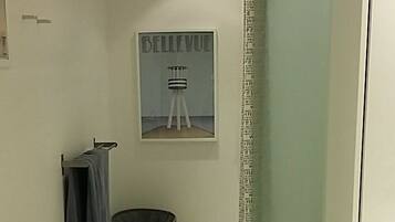 A narrow hallway with a bench, a trash bin, a towel rack, and a framed picture on the wall.