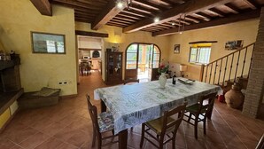 Un comedor rústico con una mesa grande, sillas de madera y suelo de baldosas.