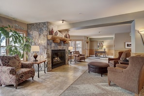 A spacious living room with a stone fireplace, comfortable seating, and a view of the outdoors.