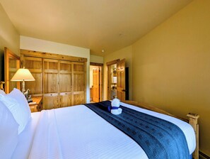 Habitación de hotel con una cama grande, armario de madera, escritorio con lámpara y televisión.
