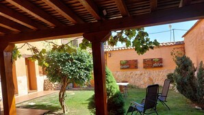 Un patio abrité avec une pergola en bois, un petit arbre et un espace détente comprenant deux chaises.