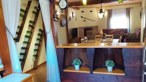 Un salon chaleureux avec un plafond en bois, un coin repas avec une longue table et une cuisine avec un mur en briques et des plantes en pot.