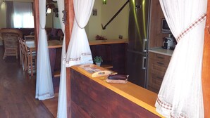 Un intérieur en bois comprenant un coin cuisine équipé d’un réfrigérateur, d’un évier et d’une table à manger avec des chaises.
