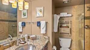Een moderne badkamer met een marmeren wastafel, een toilet en een douchecabine met glazen wanden.