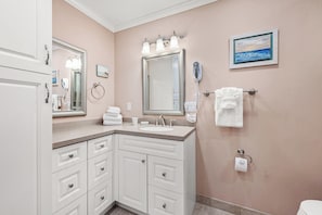 Une salle de bain avec un lavabo, un meuble-lavabo, un porte-serviettes et un tableau accroché au mur.