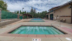 A pool area with two pools, a covered seating area, and a building with a sign. - Captain Molly 3 Bedroom Condo, Centrally Located in PC, Mins to Skiing! (Park City)