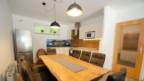 Une cuisine compacte comprenant un coin repas, un réfrigérateur, un four à micro-ondes et une table en bois avec des chaises.