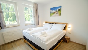 Un lit double avec du linge de lit et des serviettes blanches, une tête de lit en bois et un tableau au mur.