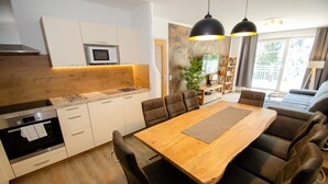 Une cuisine moderne avec une table à manger en bois, des chaises noires et des luminaires suspendus.