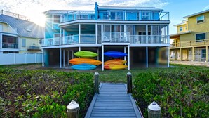 A multi-story building with a dock leading to a pool area. - Stunning Bay View's 3/2 home,10min Walk to beach (Fort Myers Beach)