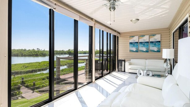 A spacious balcony with large windows overlooking a body of water and greenery. - Stunning Bay View's 3/2 home,10min Walk to beach (Fort Myers Beach)
