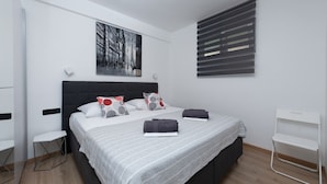 A modern bedroom with a large bed, a headboard, a side table, a chair, a window with blinds, and a painting on the wall. - Apartment in Duće with Seaview, Terrace, Air condition, WIFI (3423-6) (Duce)