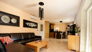 A modern living room with a black leather sofa, a wooden coffee table, and artwork on the walls. - Villa Bianca, Tar | Private Pool Villa in Istria (Rogovici)