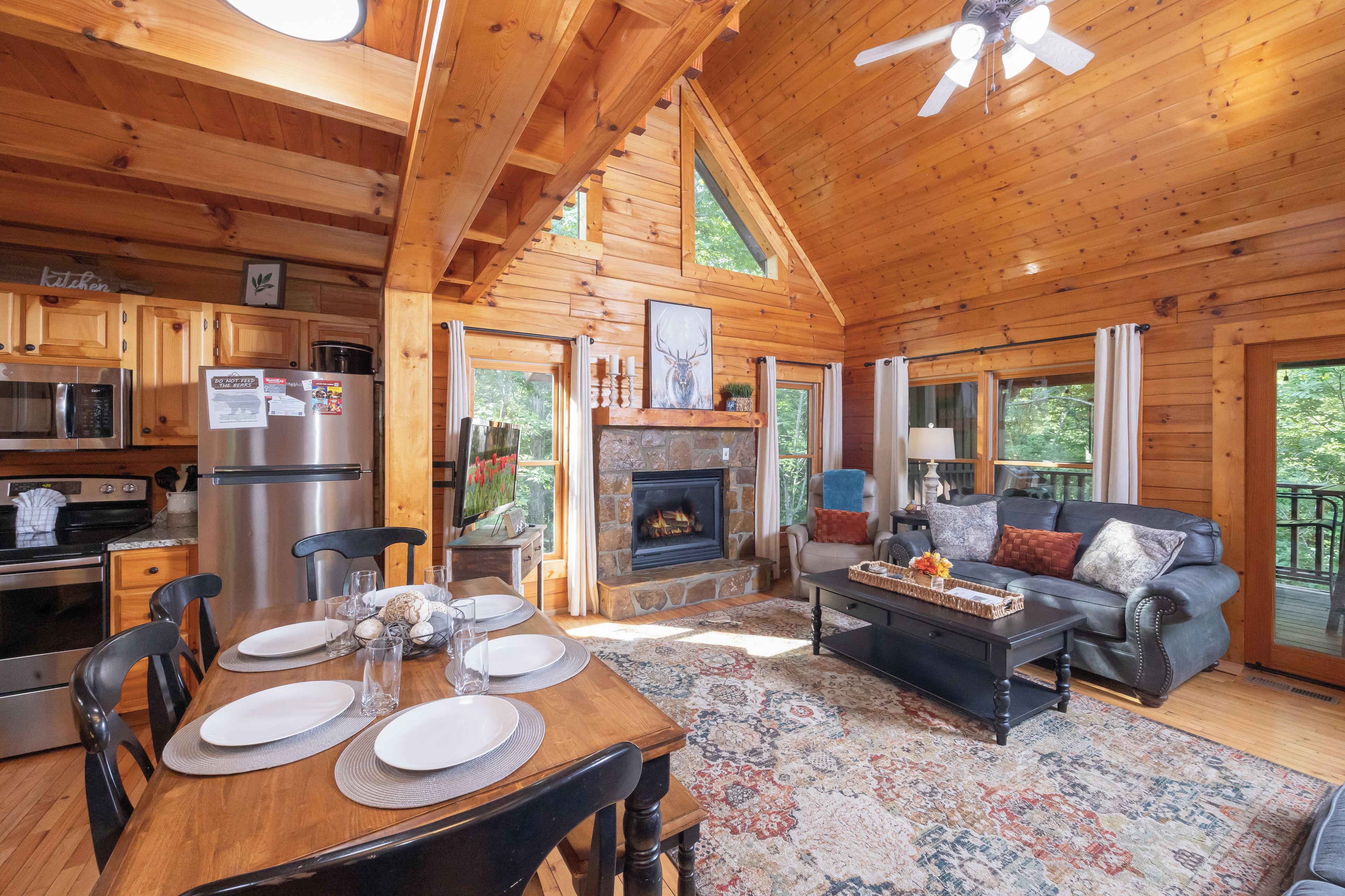 L’intérieur d’un chalet en bois comprend un coin repas, une cuisine, une cheminée et un salon avec un canapé.