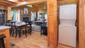L'intérieur d'une cabane en bois comprend un coin repas, une cuisine et une grande fenêtre.