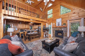 A spacious cabin with a high ceiling, a dining area, a fireplace, and a cozy seating area. - Smoky Mtn Views! Hot Tub, Pool Table, Arcade Game. Resort Pool/Putt Putt/Fishing (Sevierville)