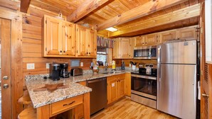 A wooden cabin kitchen with granite countertops, stainless steel appliances, and wooden cabinets. - Great Mountain Views! 5miles to Pigeon Forge - Pool, Fishing, Putt Putt, Golf (Sevierville)